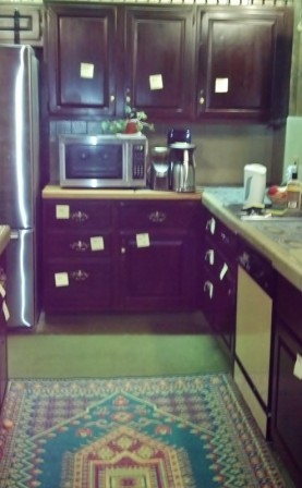 picture looking at kitchen cabinets with multiple yellow post-its hanging on the cabinets and drawers